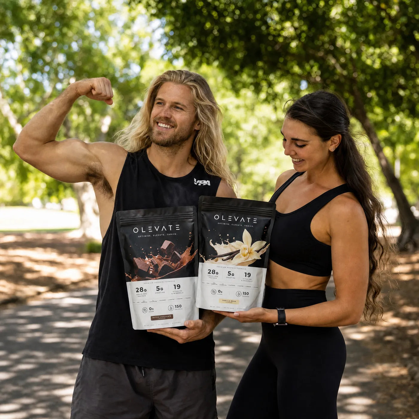 Two people outdoors holding OLEVATE vanilla and chocolate pouches