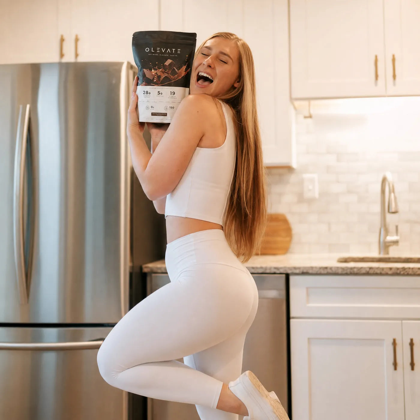 A person in a kitchen holding the OLEVATE chocolate pouch